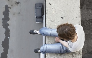 A women siting on the edge of a building, mentally preparing herself to jump.